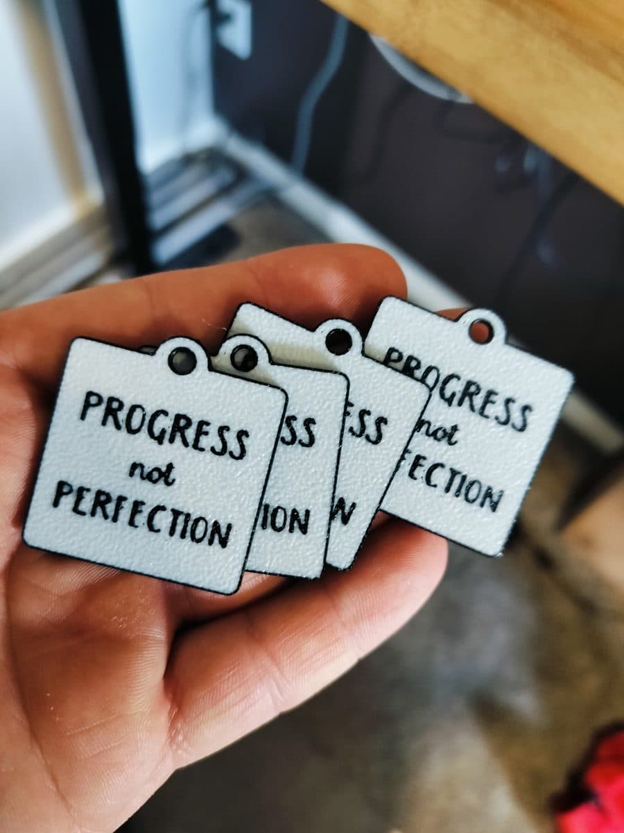 Printed "Progress not Perfection" tags in hand